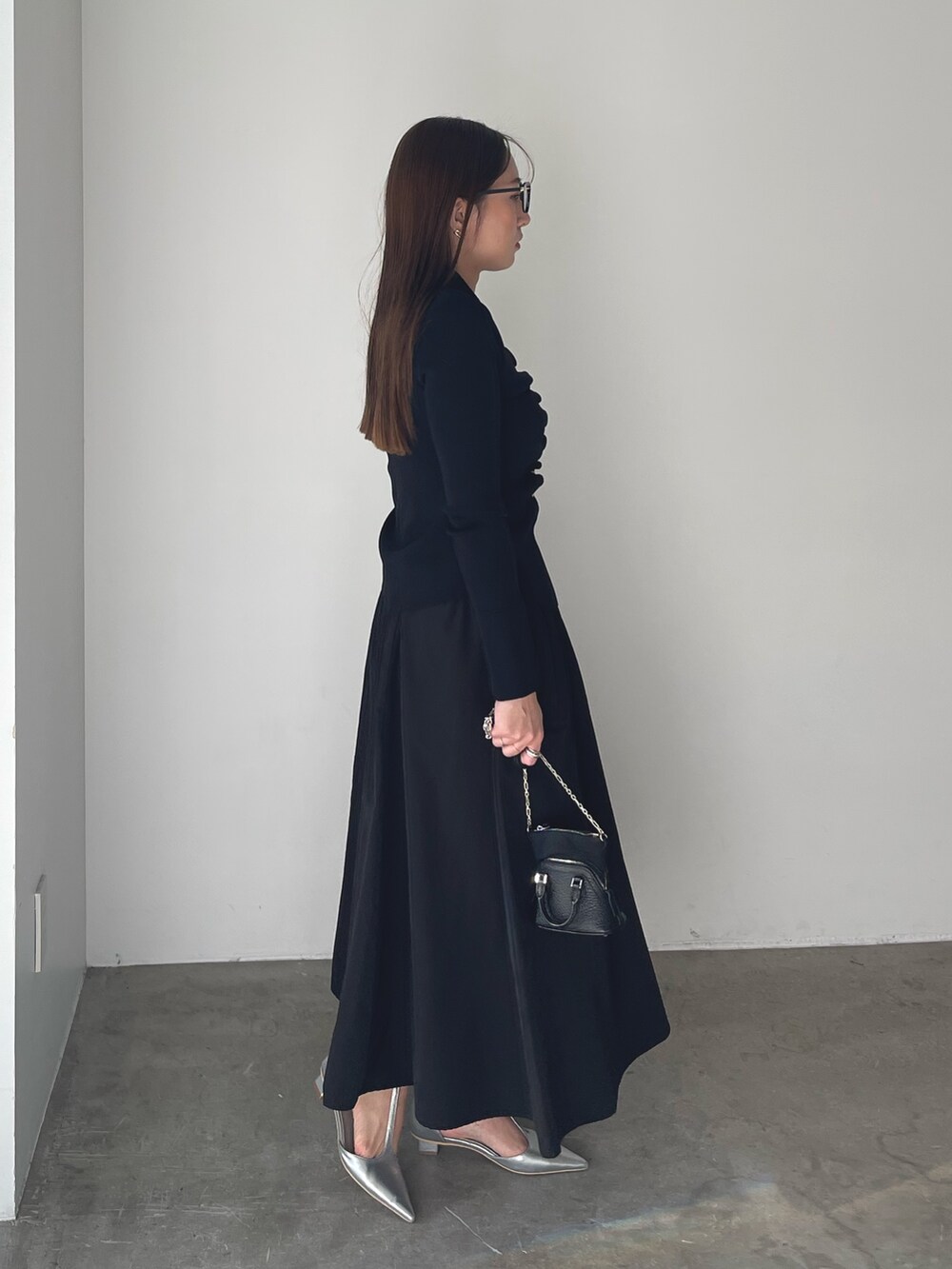 シルバー系のパンプス、ブラック系のワンピース、ゴールド系のピアス（両耳用）を着用したレディースの冬コーディネートの6枚目の写真