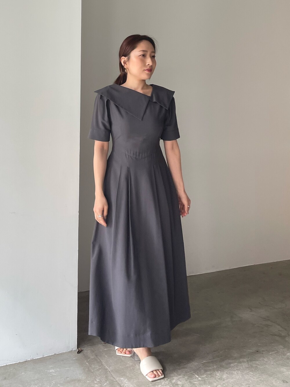 ホワイト系のサンダル、グレー系のワンピース、ゴールド系のピアス（両耳用）を着用したレディースの春コーディネートの4枚目の写真