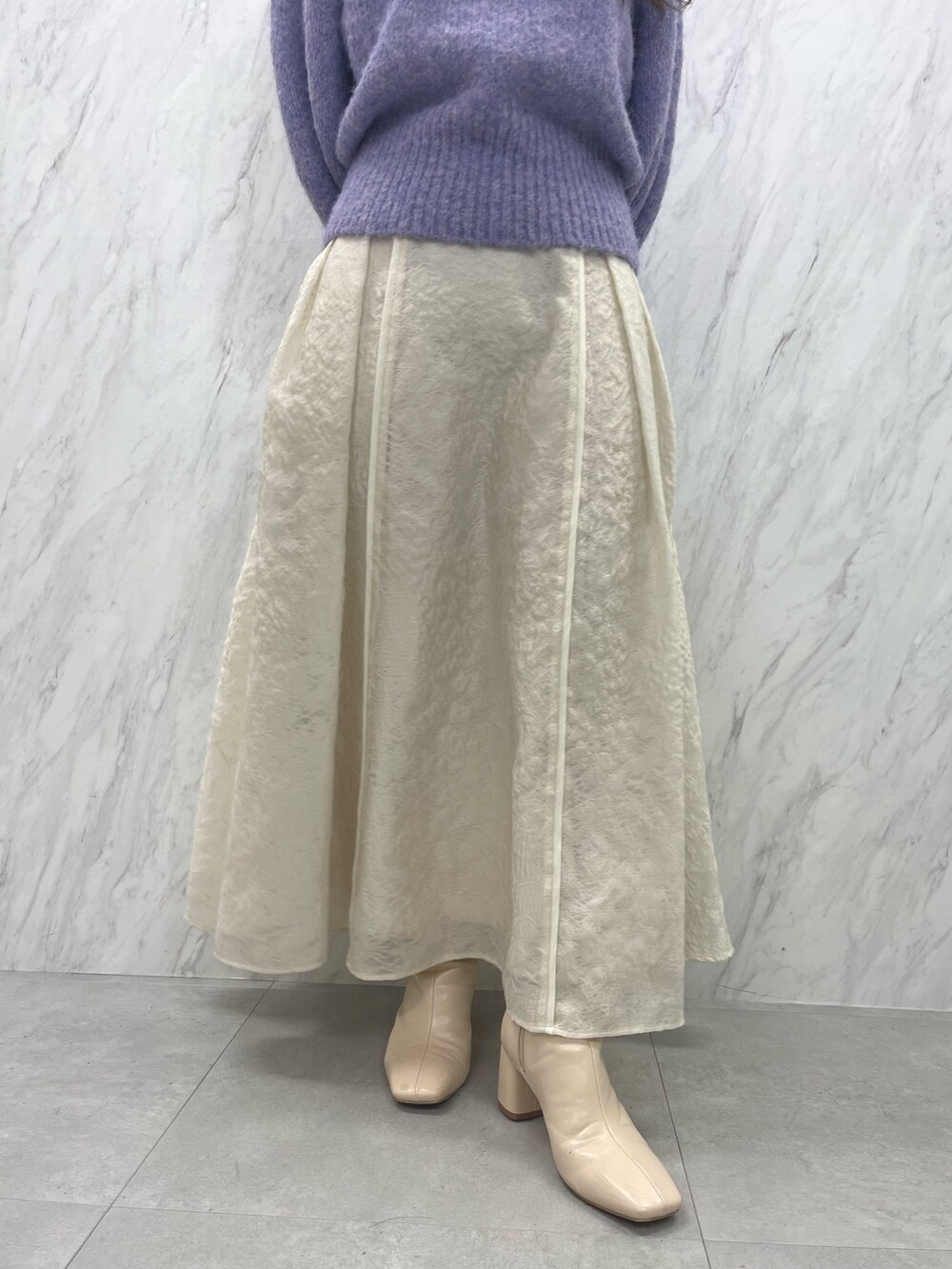 ホワイト系のスカート、ホワイト系のブーツ、パープル系のニット/セーターを着用したレディースの冬コーディネートの9枚目の写真