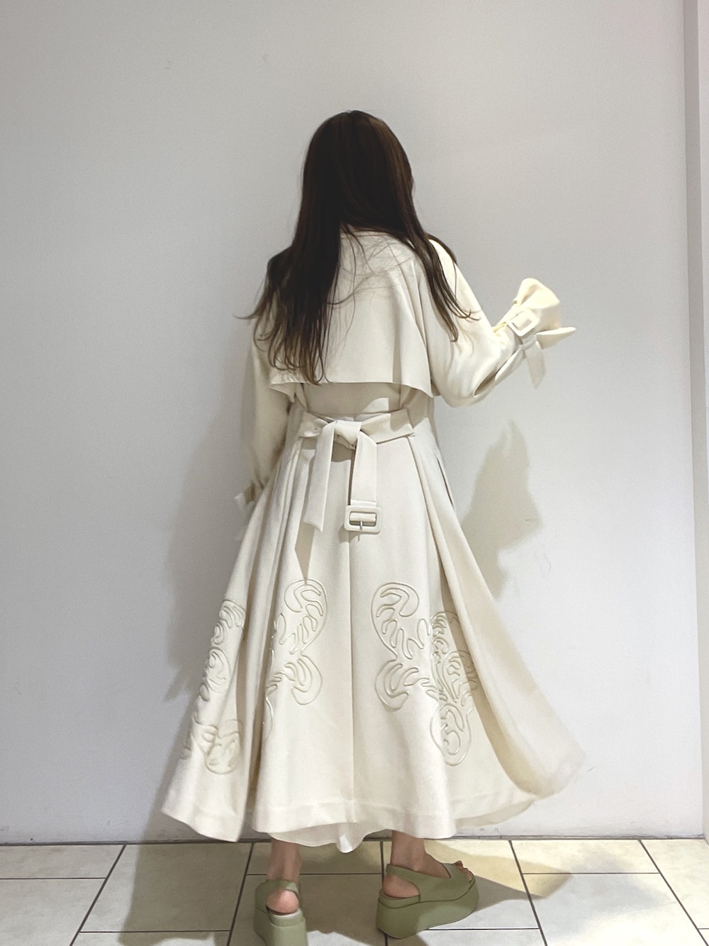 ホワイト系のトレンチコート、ベージュ系のサンダル、グリーン系のショルダーバッグを着用したレディースの冬コーディネートの7枚目の写真