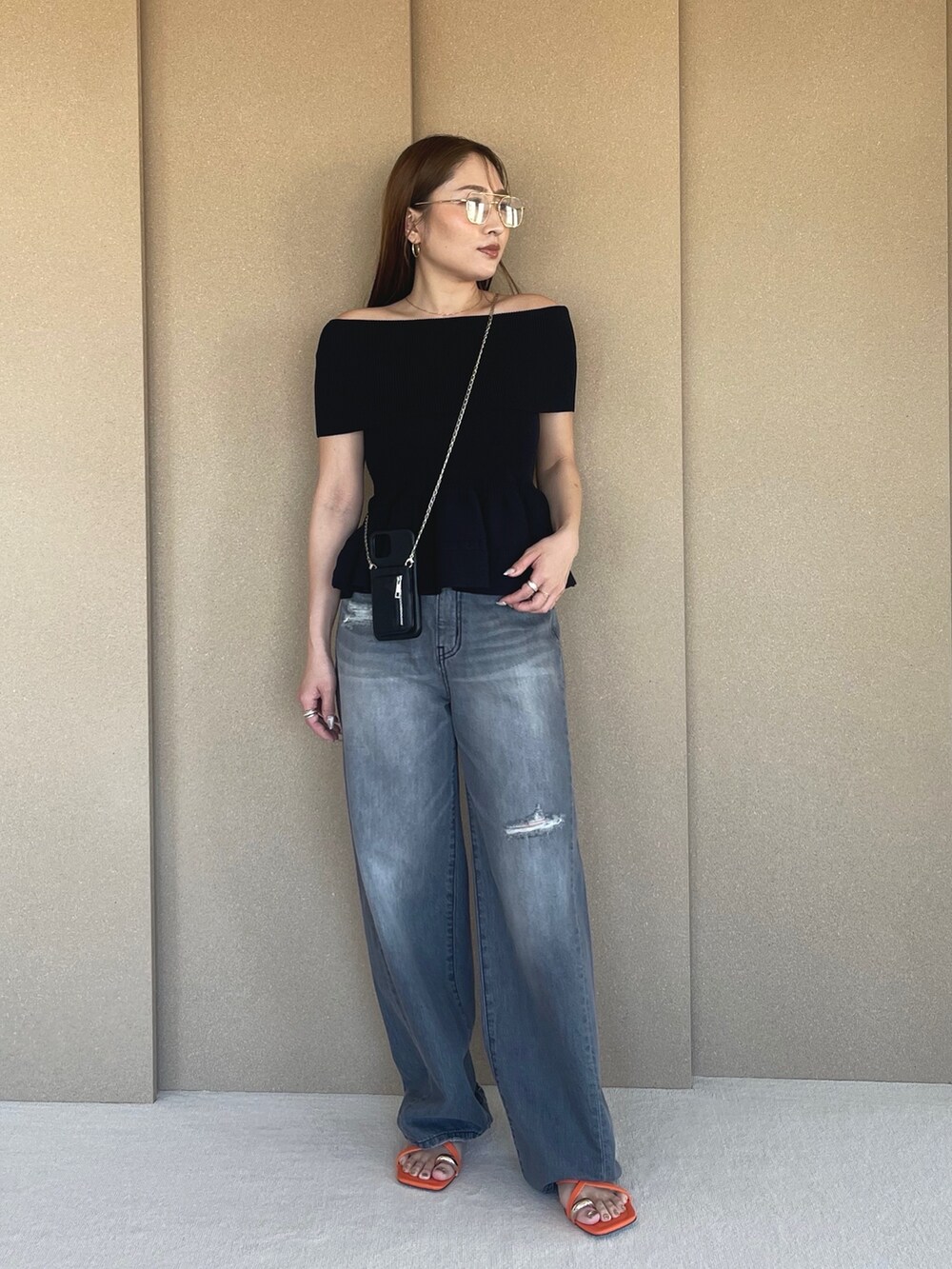 ブラック系のニット/セーター、グレー系のデニムパンツ、オレンジ系のサンダルを着用したレディースの春コーディネートの2枚目の写真