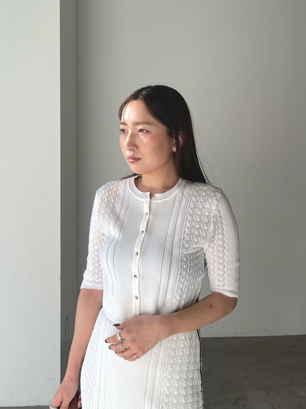 イエロー系のハンドバッグ、シルバー系のパンプス、ホワイト系のワンピースを着用したレディースの冬コーディネートの8枚目の写真