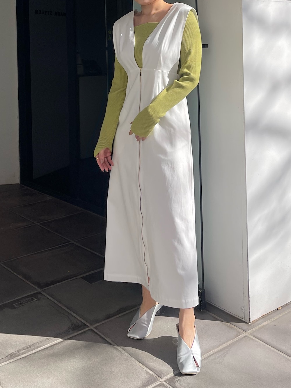 シルバー系のパンプス、グリーン系のニット/セーター、ホワイト系のジャンパースカートを着用したレディースの冬コーディネートの4枚目の写真