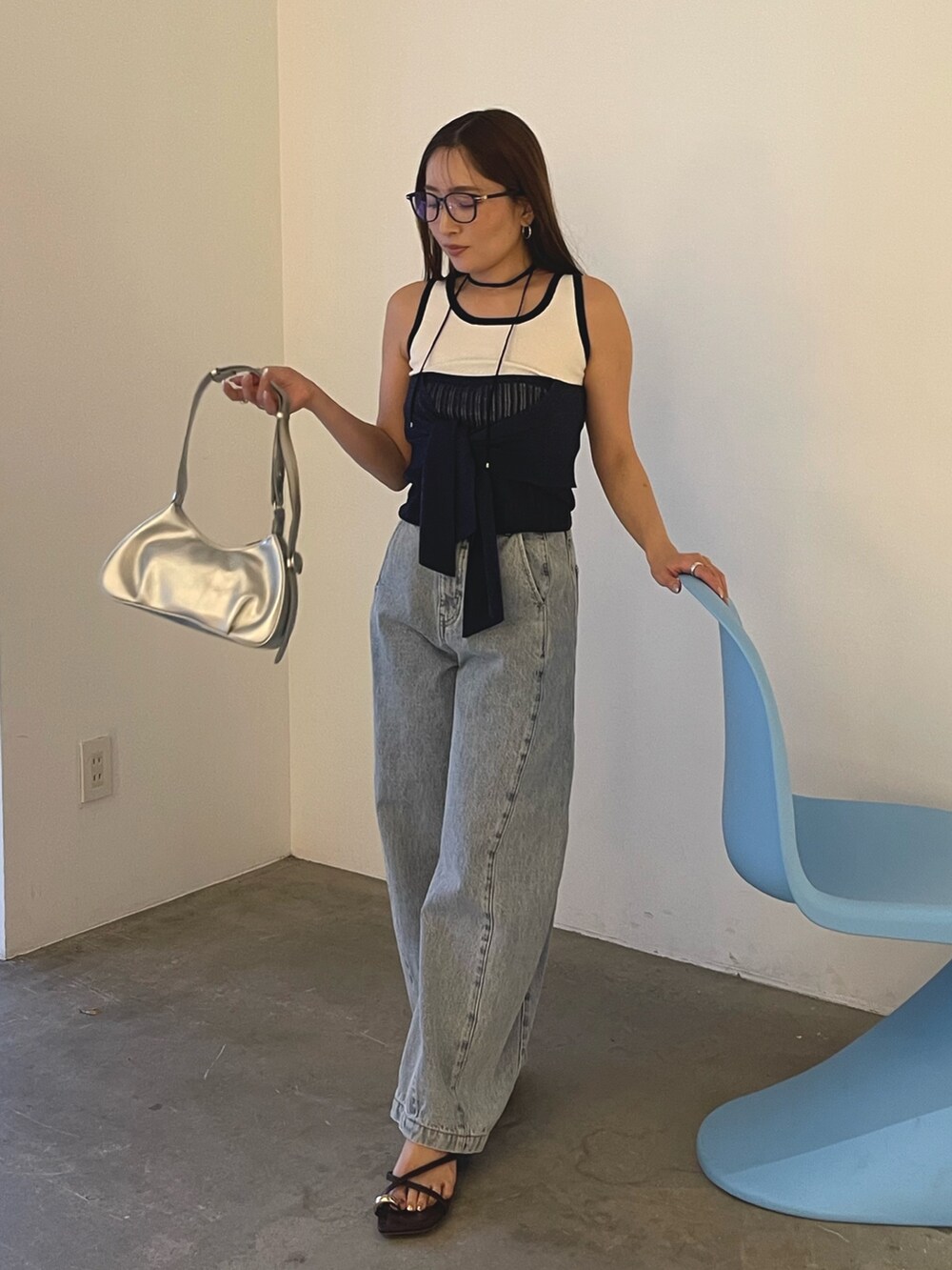 ブルー系のデニムパンツ、シルバー系のハンドバッグ、ブラウン系のサンダルを着用したレディースの春コーディネートの2枚目の写真