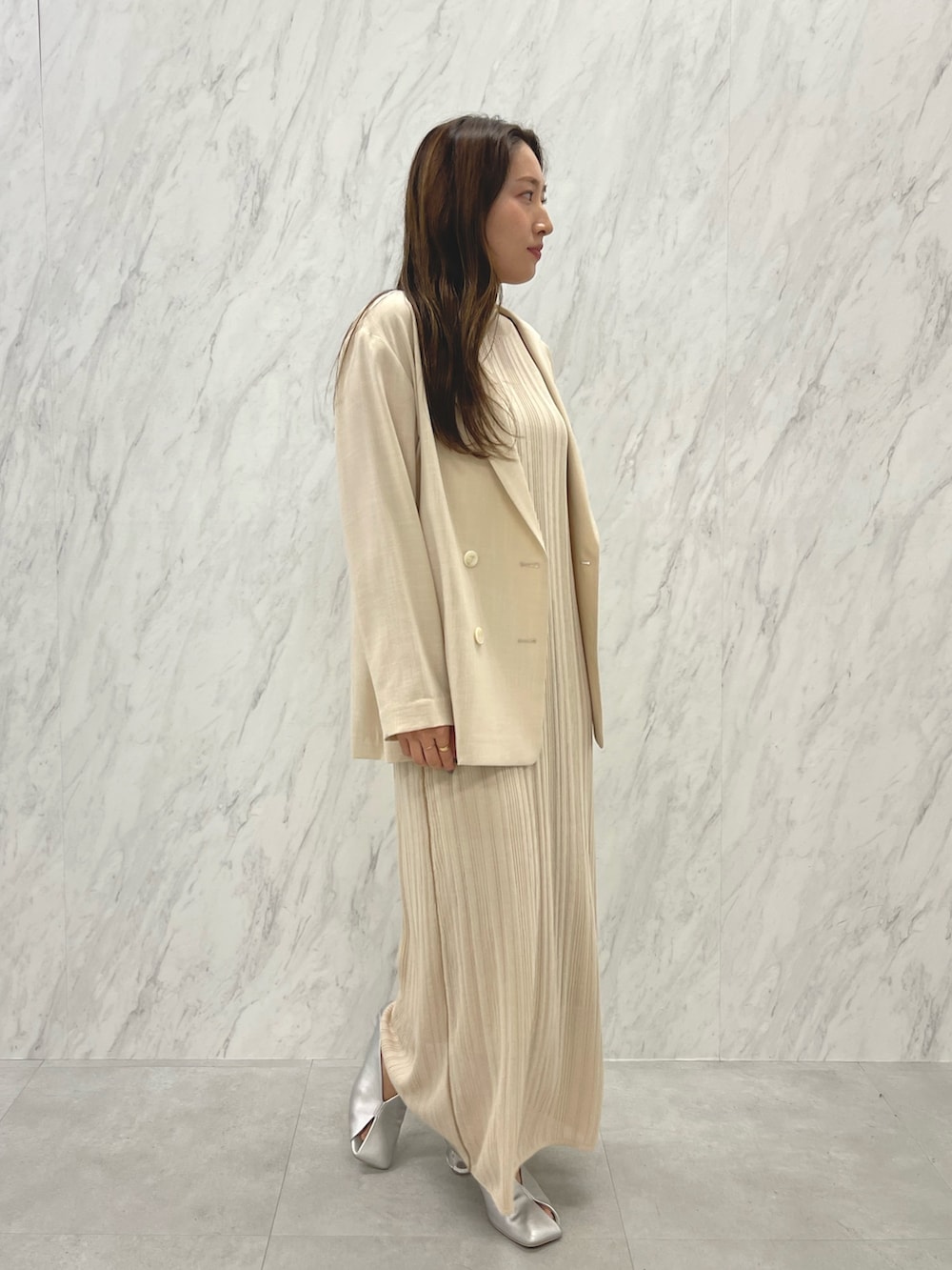 シルバー系のパンプス、ベージュ系のテーラードジャケット、ホワイト系のワンピースを着用したレディースの春コーディネートの6枚目の写真