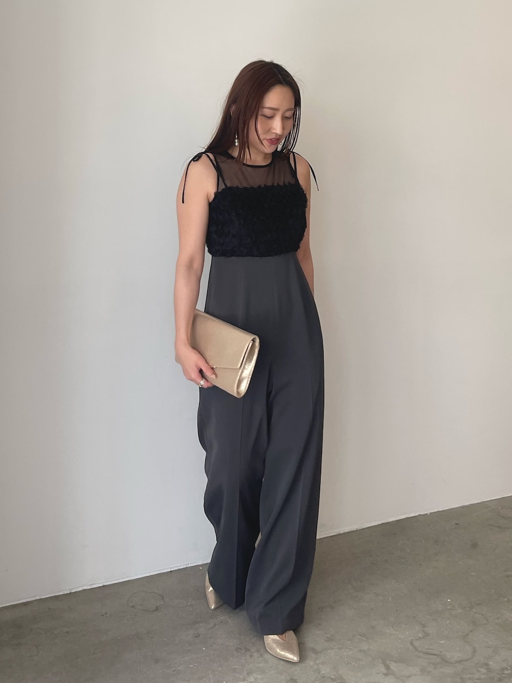 グレー系のパンツドレス、ゴールド系のパンプス、ゴールド系のクラッチバッグを着用したレディースの春コーディネートの3枚目の写真