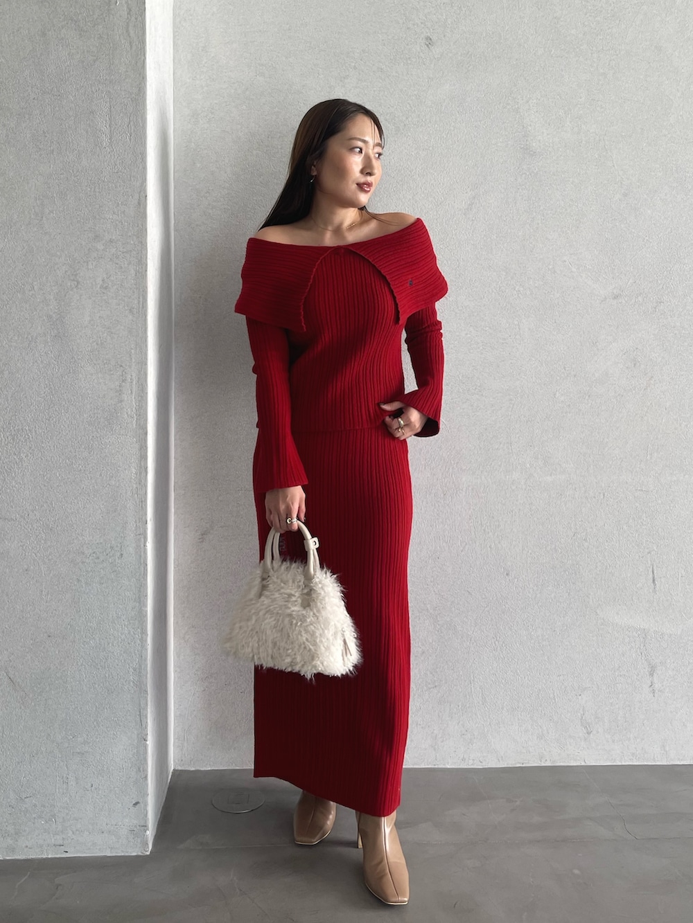 レッド系のニット/セーター、ベージュ系のブーツ、レッド系のスカートを着用したレディースの秋コーディネートの4枚目の写真