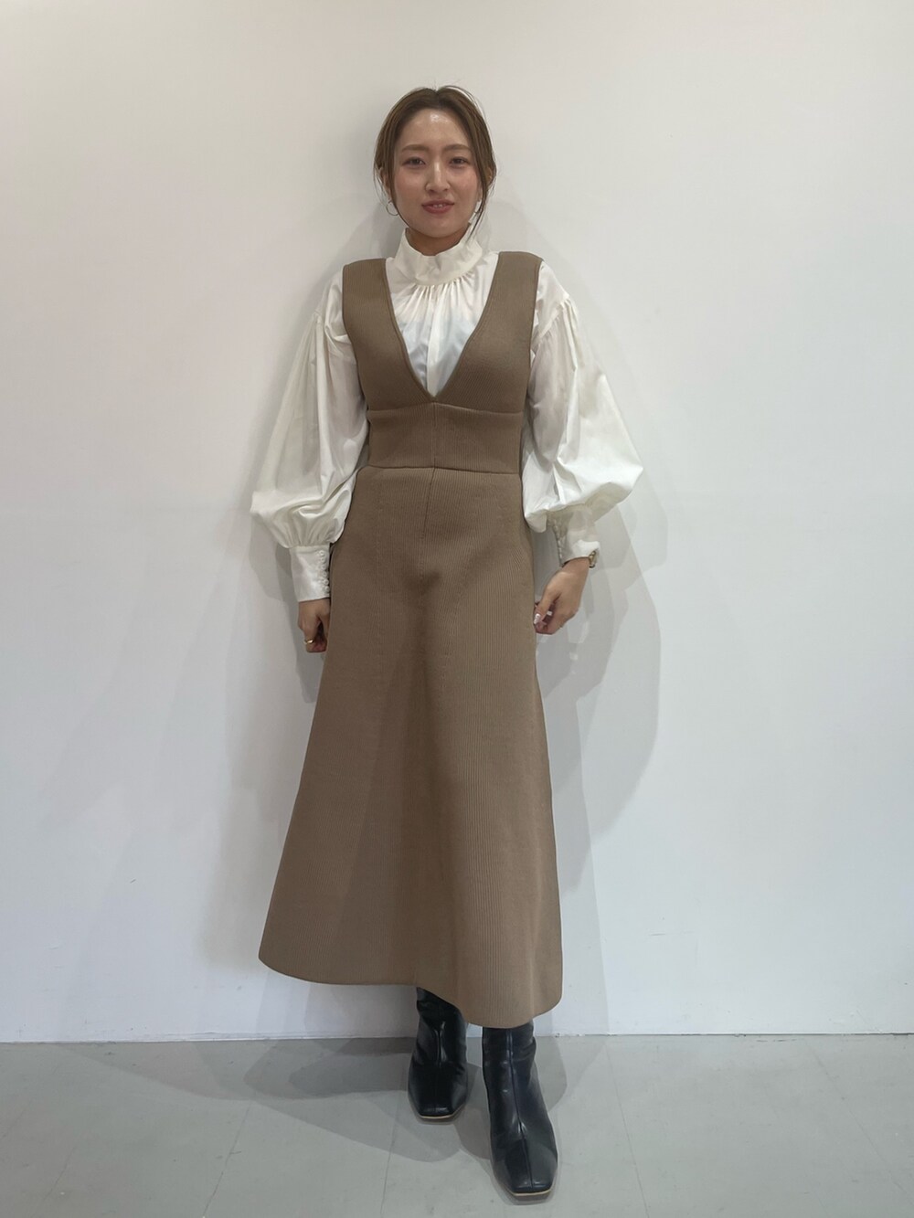 ブラック系のブーツ、ベージュ系のジャンパースカート、ホワイト系のシャツ/ブラウスを着用したレディースの秋コーディネートの3枚目の写真