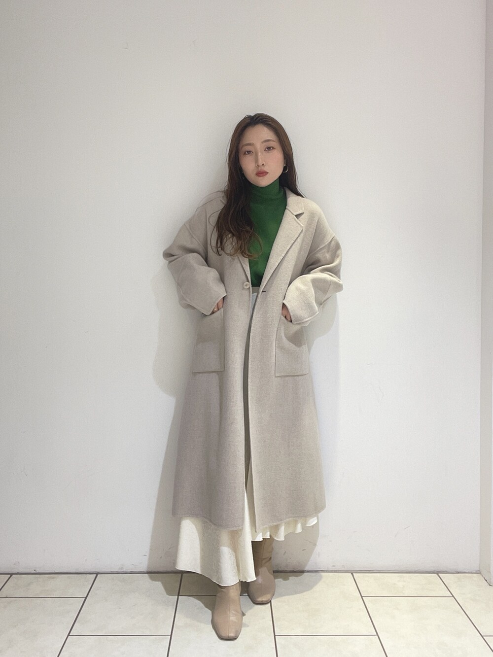 ホワイト系のスカート、ベージュ系のその他アウター、グリーン系のニット/セーターを着用したレディースの冬コーディネートの9枚目の写真