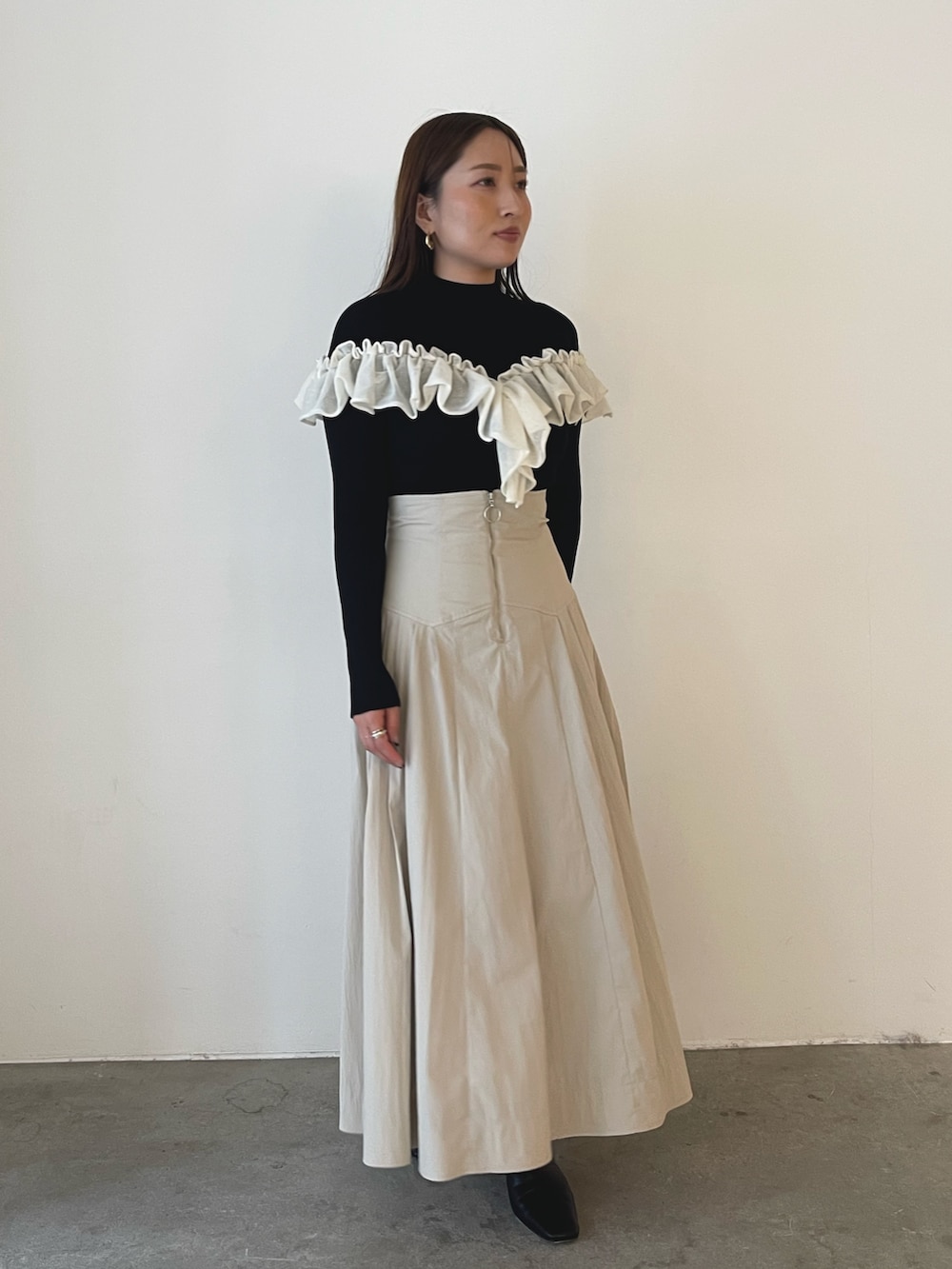 ブラック系のブーツ、ホワイト系のスカート、ブラック系のニット/セーターを着用したレディースの秋コーディネートの4枚目の写真