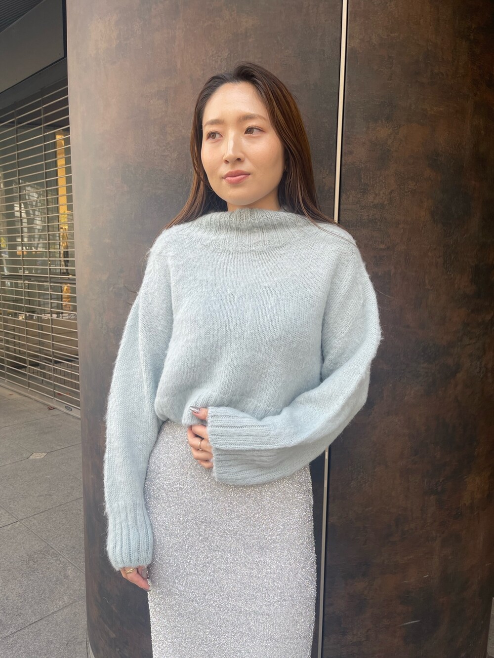 シルバー系のスカート、ブラック系のブーツ、グリーン系のニット/セーターを着用したレディースの冬コーディネートの6枚目の写真