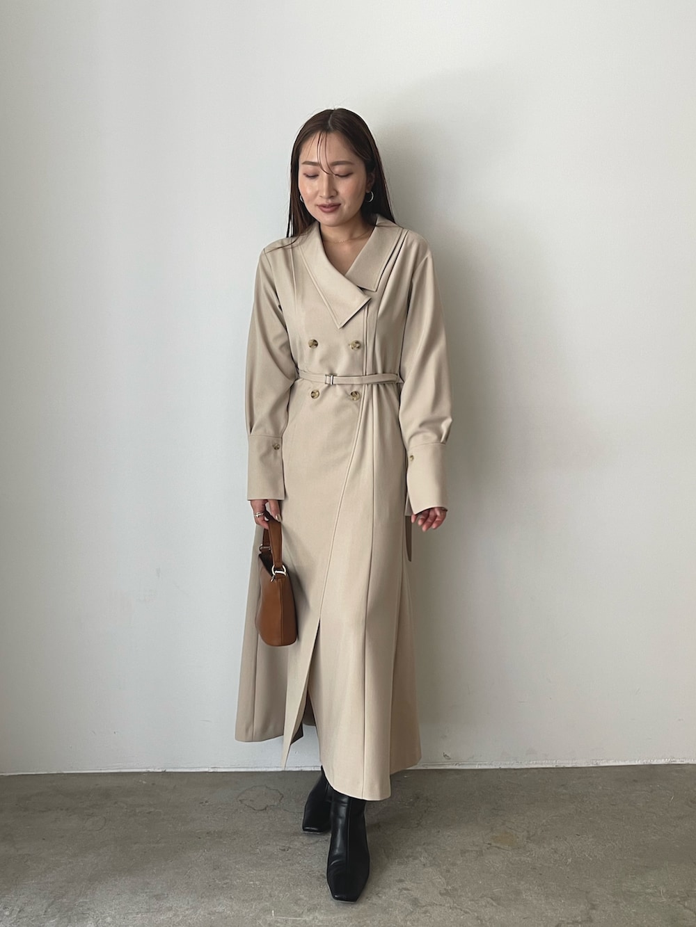 イエロー系のハンドバッグ、ブラック系のブルゾン、ベージュ系のワンピースを着用したレディースの秋コーディネートの7枚目の写真