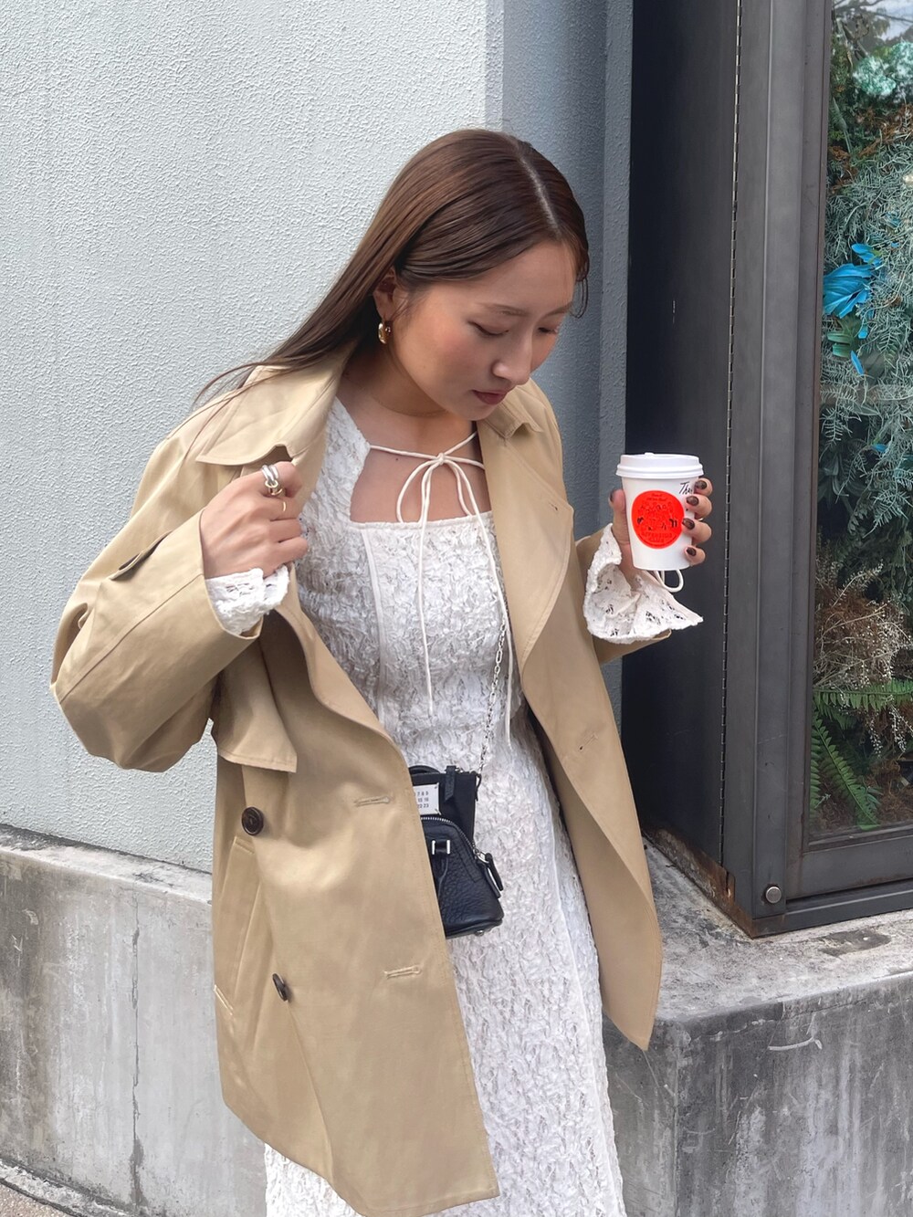 ホワイト系のワンピース、ベージュ系のトレンチコート、ゴールド系のピアス（両耳用）を着用したレディースの冬コーディネートの7枚目の写真