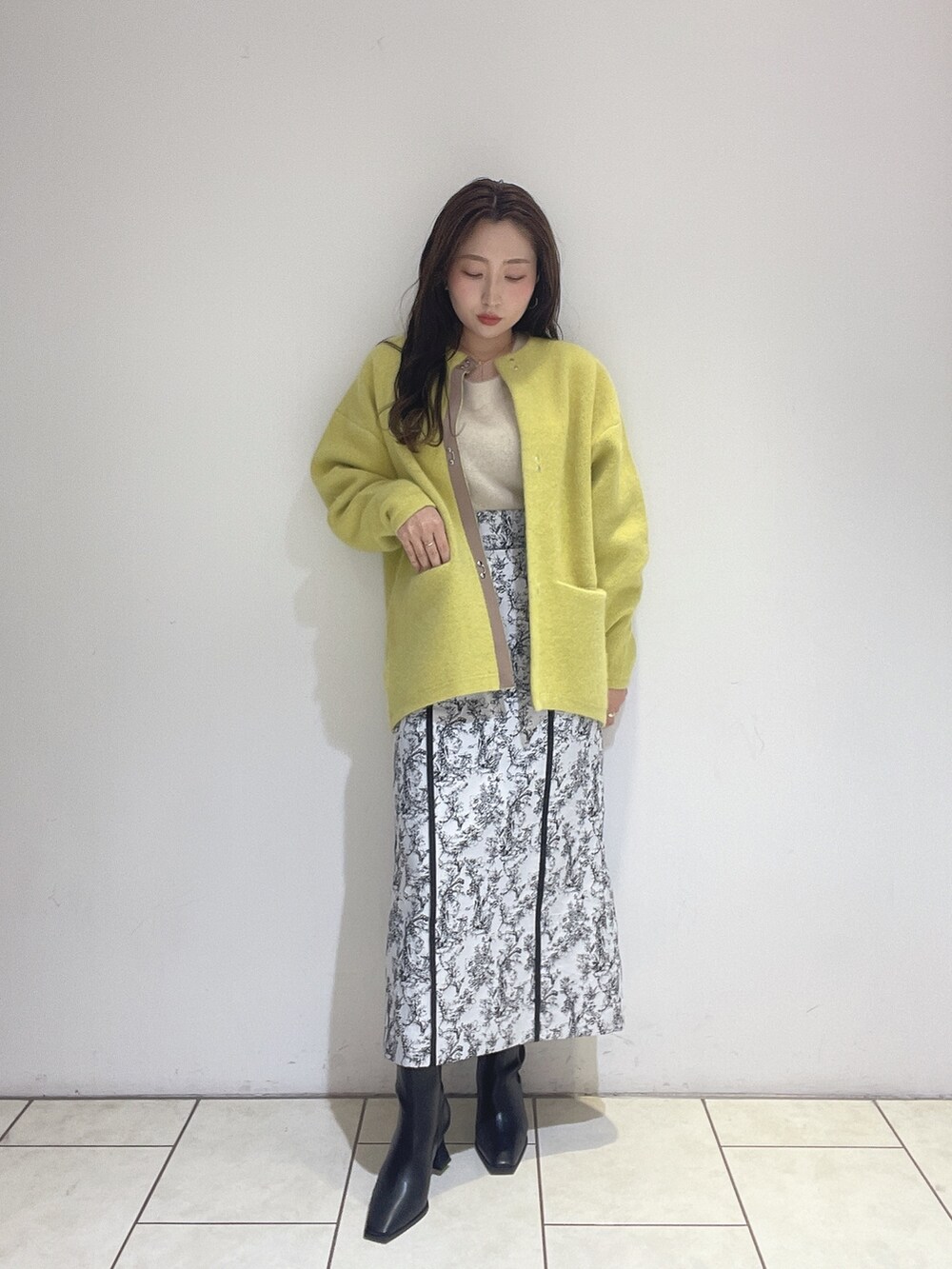 イエロー系のカーディガン/ボレロ、ブラック系のスカート、ホワイト系のニット/セーターを着用したレディースの秋コーディネートの3枚目の写真