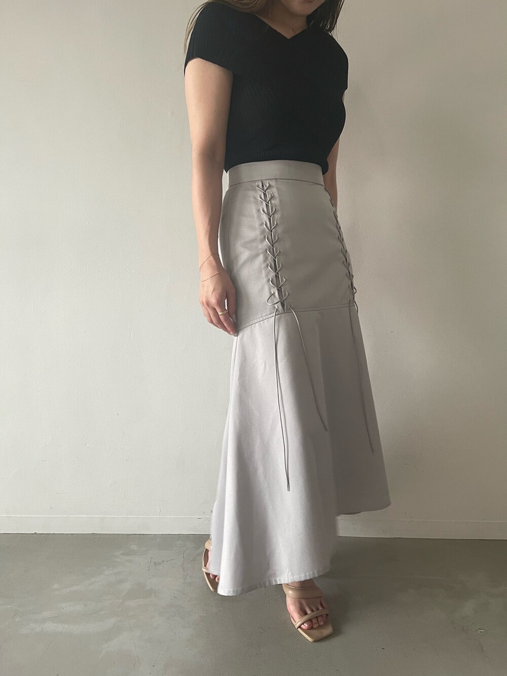 ブラック系のニット/セーター、グレー系のスカート、ベージュ系のサンダルを着用したレディースの夏コーディネートの4枚目の写真