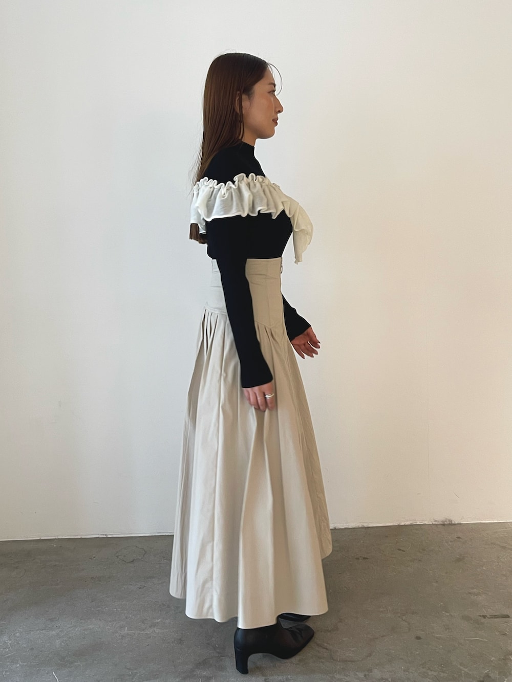 ブラック系のブーツ、ホワイト系のスカート、ブラック系のニット/セーターを着用したレディースの秋コーディネートの5枚目の写真