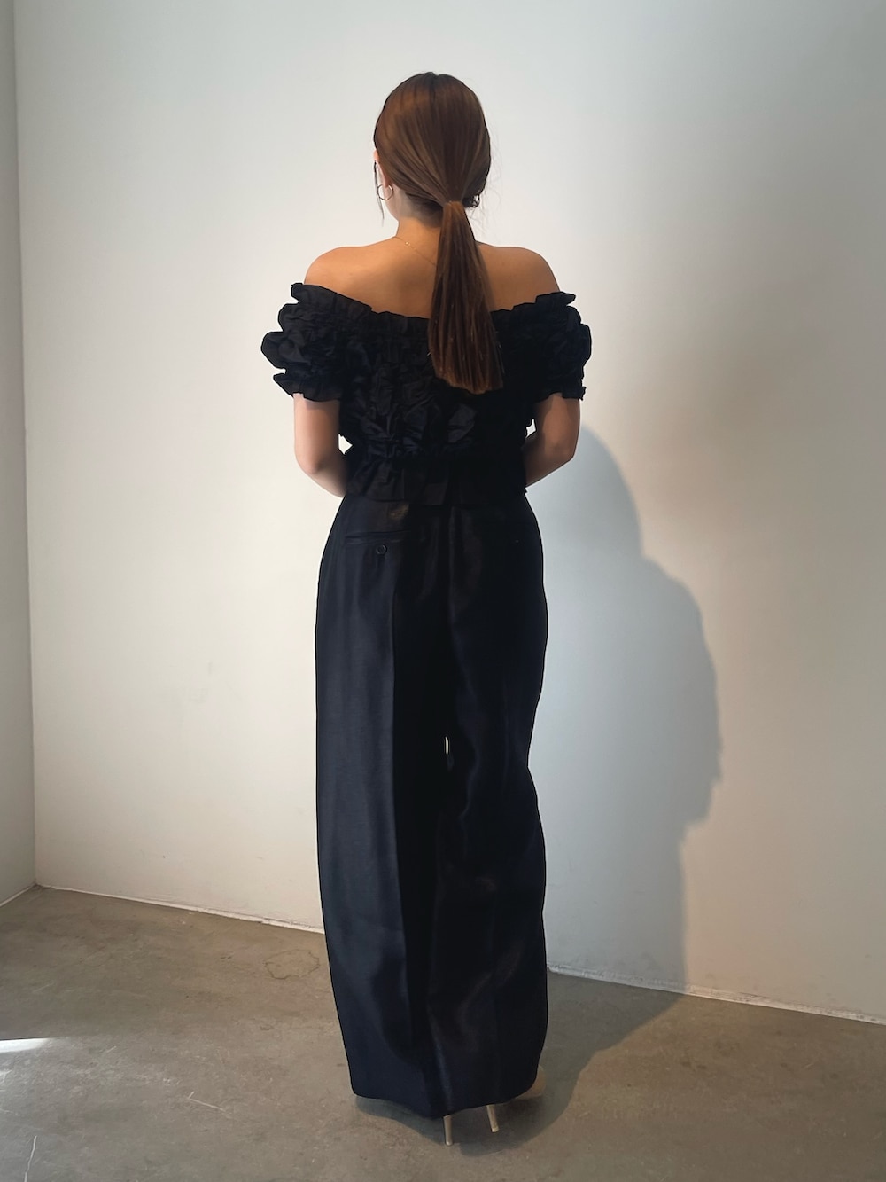 ブラック系のハンドバッグ、ゴールド系のパンプス、ブラック系のパンツドレスを着用したレディースの春コーディネートの7枚目の写真