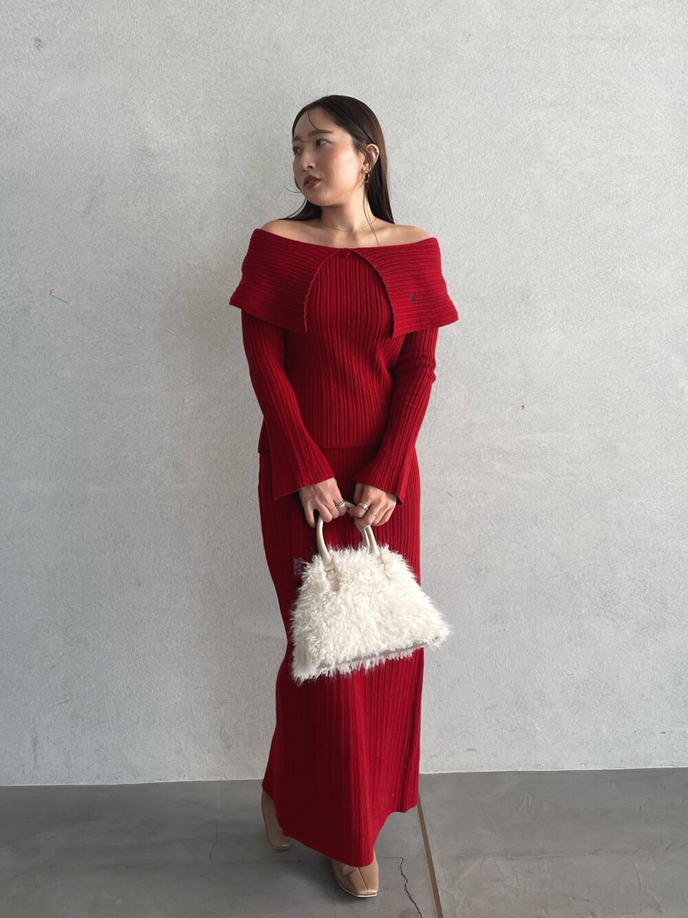 レッド系のニット/セーター、ベージュ系のブーツ、レッド系のスカートを着用したレディースの秋コーディネートの3枚目の写真