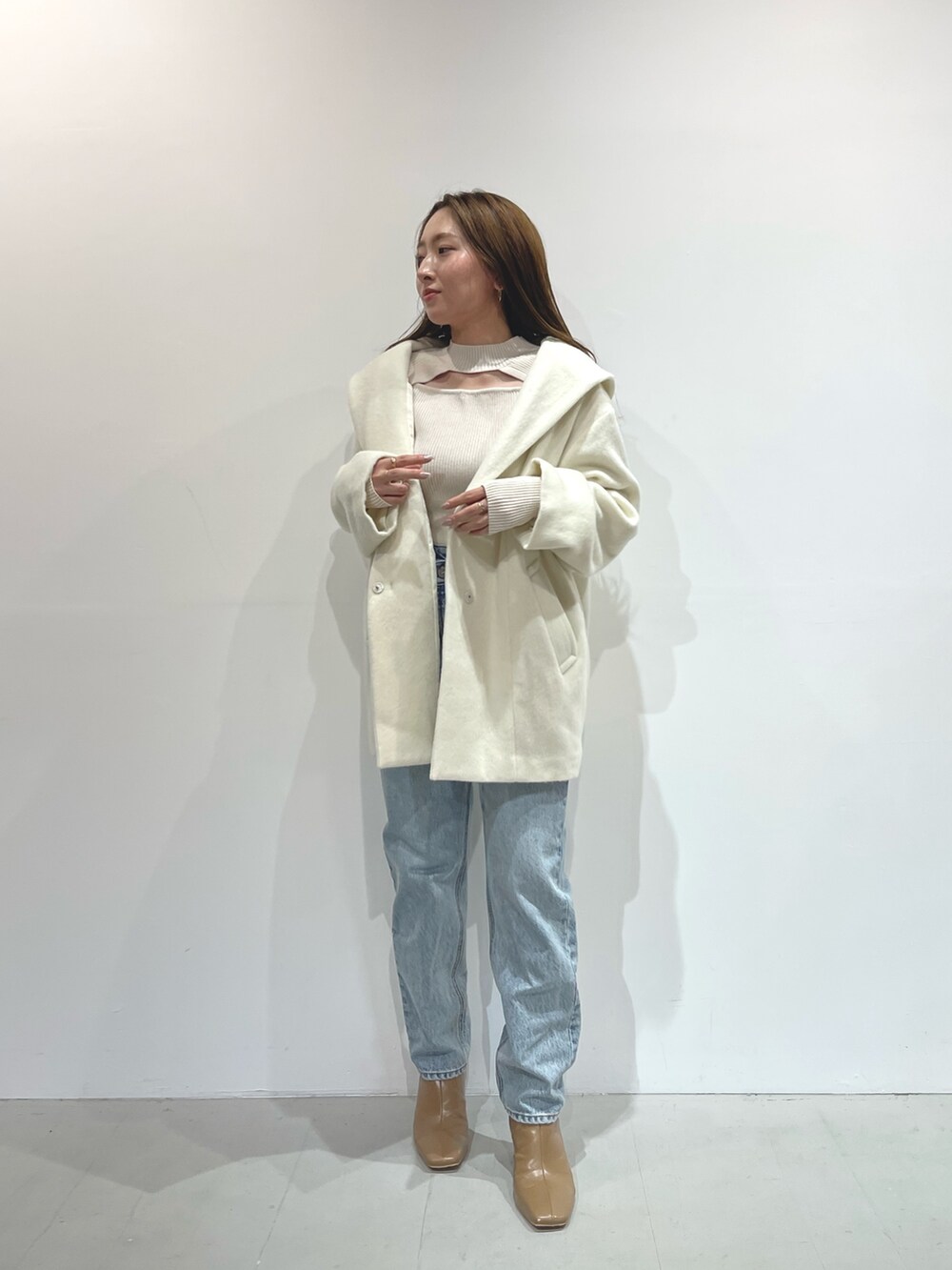 ホワイト系のニット/セーター、ベージュ系のブーツ、ホワイト系のその他アウターを着用したレディースの秋コーディネートの6枚目の写真