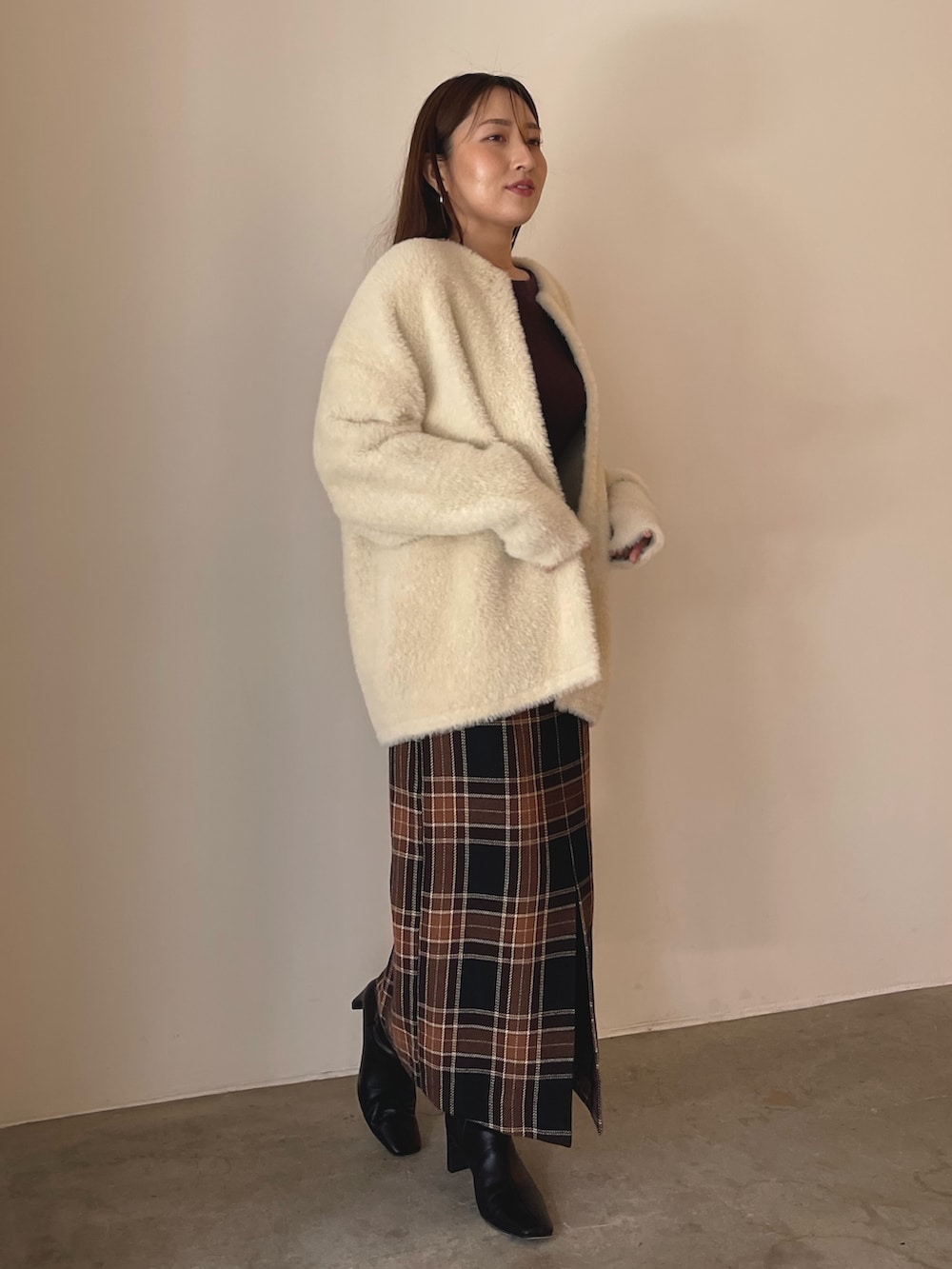 ブラウン系のニット/セーター、ブラウン系のスカート、ブラック系のブーツを着用したレディースの秋コーディネートの4枚目の写真