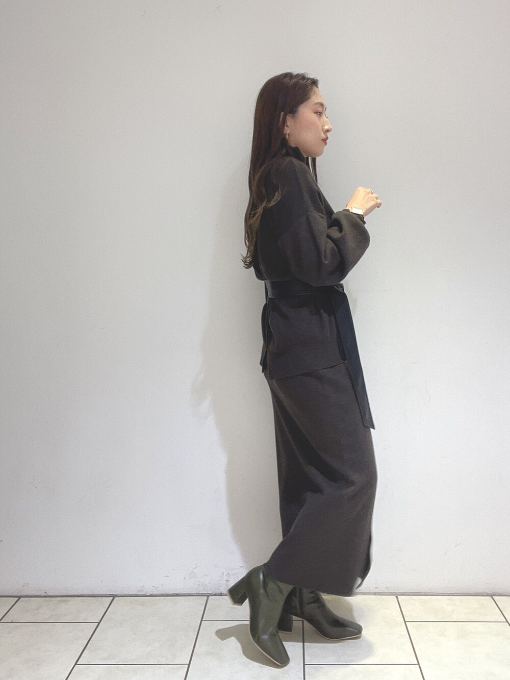 ブラウン系のニット/セーター、ブラウン系のスカート、グリーン系のブーツを着用したレディースの冬コーディネートの7枚目の写真