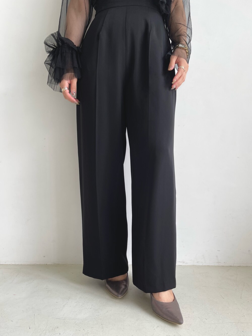 ブラック系のパンツドレス、シルバー系のパンプスを着用したレディースの秋コーディネートの7枚目の写真