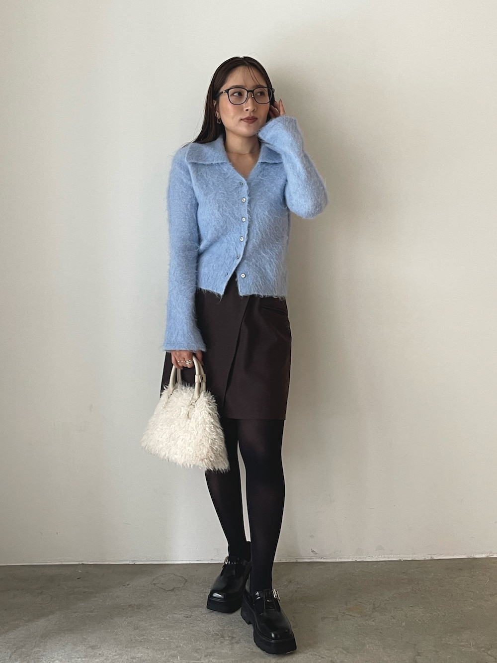 ホワイト系のボストンバッグ、ブラウン系のスカート、ブラック系のローファーを着用したレディースの秋コーディネートの2枚目の写真