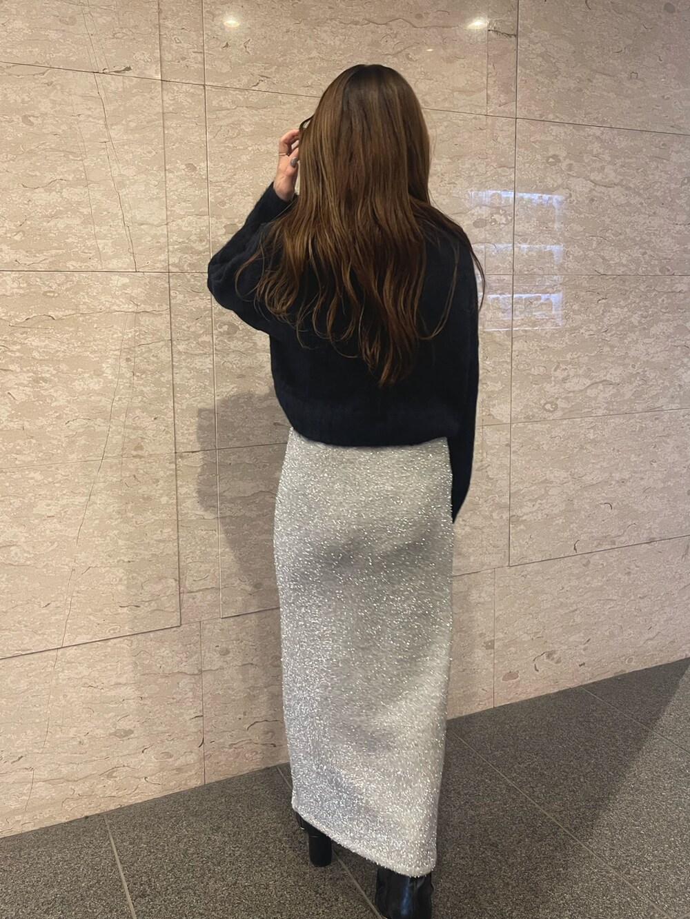 ブラック系のブーツ、ブルー系のニット/セーター、シルバー系のスカートを着用したレディースの冬コーディネートの3枚目の写真