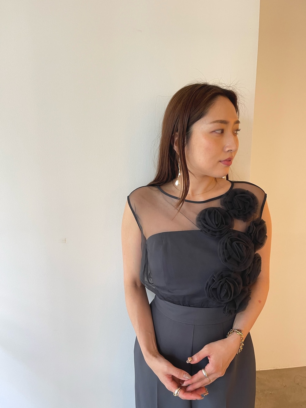 シルバー系のパンプス、グレー系のパンツドレス、ゴールド系のピアス（両耳用）を着用したレディースの夏コーディネートの5枚目の写真