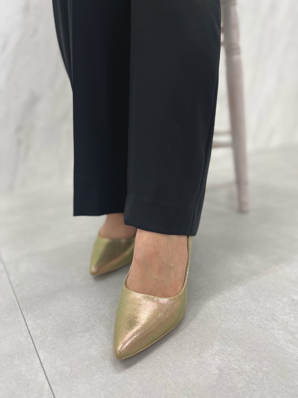 ブラック系のパンツドレス、ゴールド系のパンプスを着用したレディースの冬コーディネートの9枚目の写真