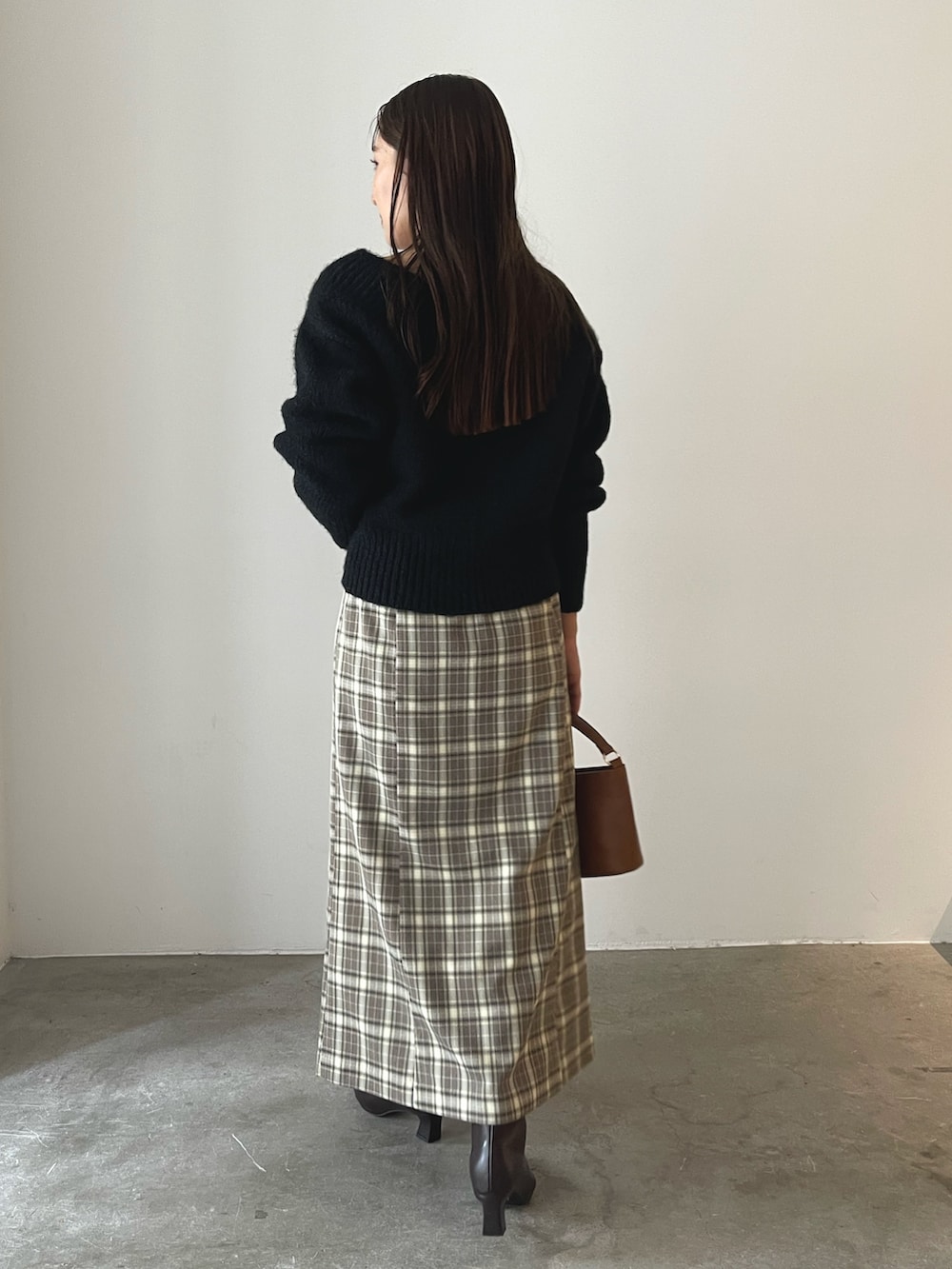 イエロー系のハンドバッグ、ブラウン系のブーツ、ブラウン系のスカートを着用したレディースの秋コーディネートの6枚目の写真