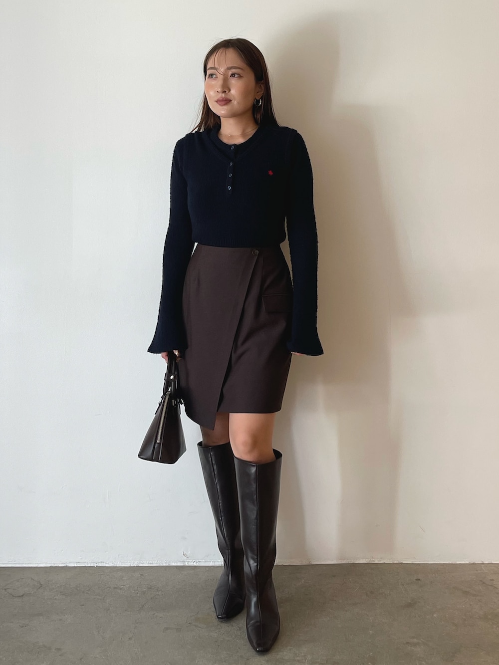 ブラウン系のボストンバッグ、ブラウン系のスカート、ブルー系のニット/セーターを着用したレディースの夏コーディネートの3枚目の写真