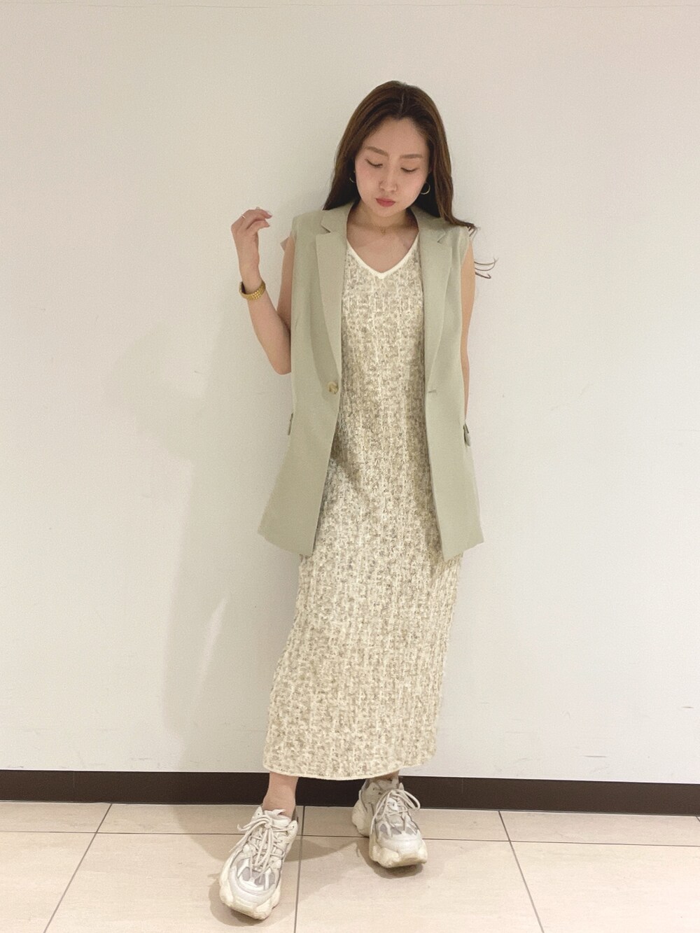 ホワイト系のワンピース、ベージュ系のベストを着用したレディースの春コーディネートの2枚目の写真