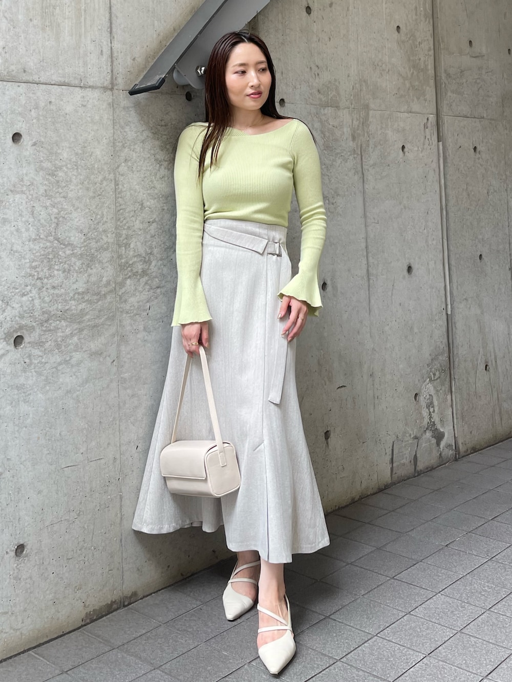 ホワイト系のショルダーバッグ、ホワイト系のパンプス、グレー系のスカートを着用したレディースの秋コーディネートの3枚目の写真