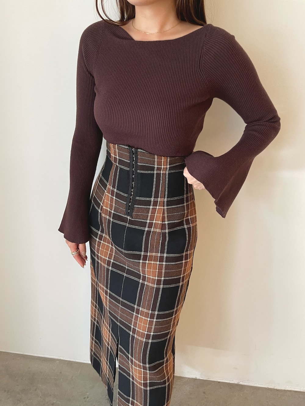 ブラウン系のニット/セーター、ブラウン系のスカート、ブラック系のブーツを着用したレディースの秋コーディネートの9枚目の写真