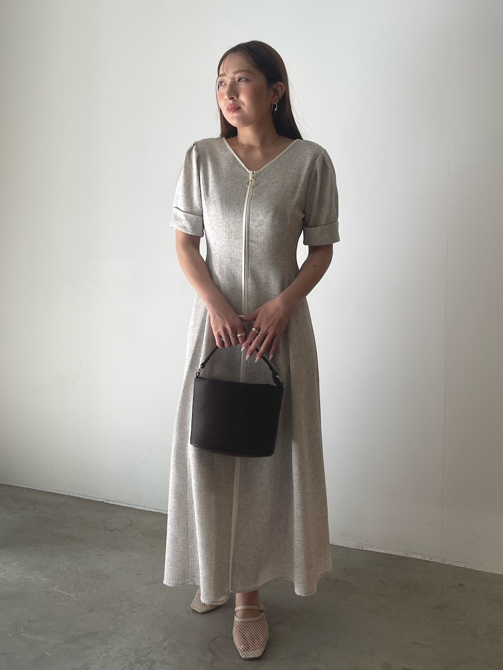 ブラウン系のハンドバッグ、ホワイト系のワンピースを着用したレディースの冬コーディネートの2枚目の写真