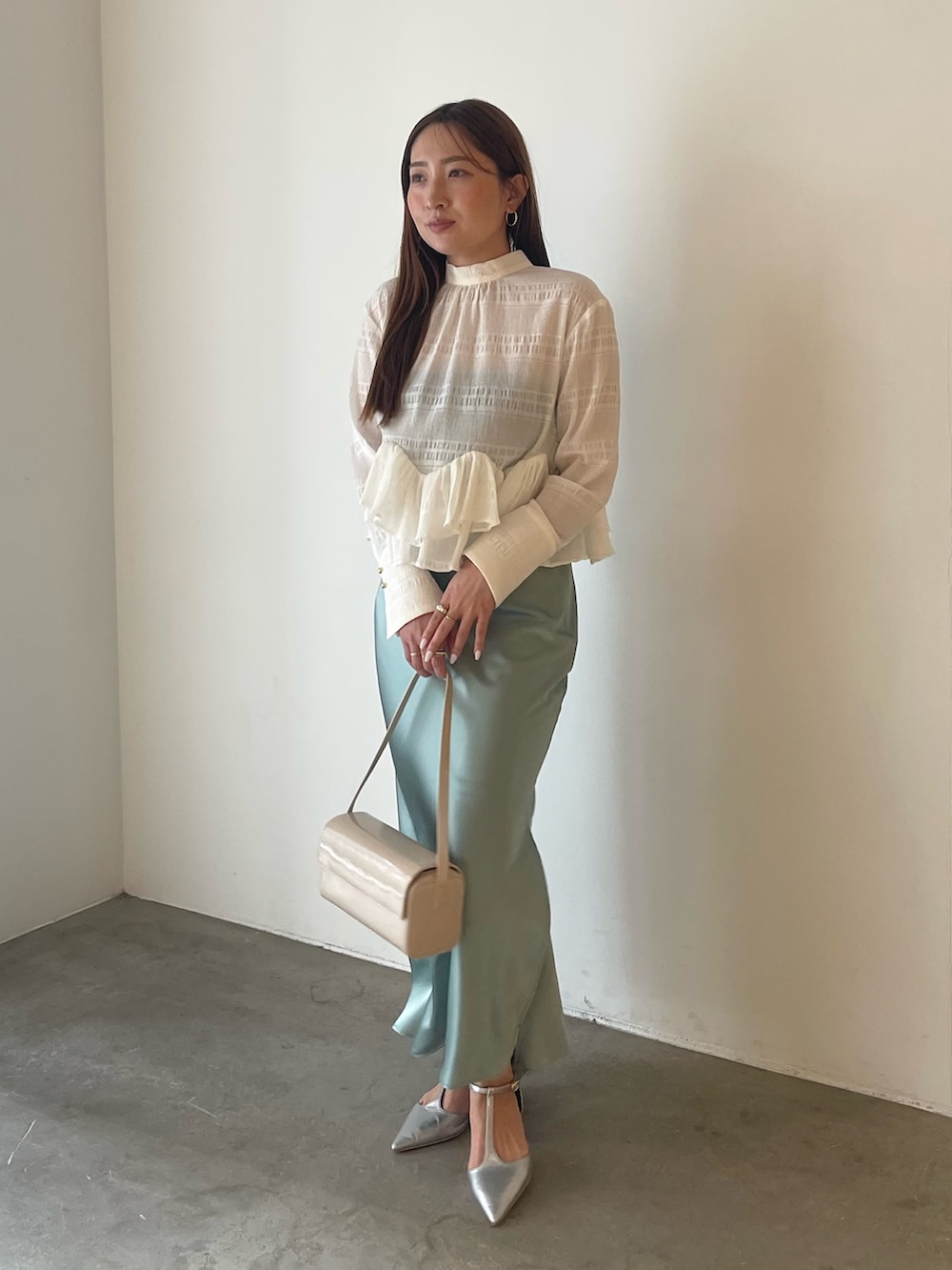 シルバー系のパンプス、ホワイト系のシャツ/ブラウス、グリーン系のスカートを着用したレディースの冬コーディネートの4枚目の写真