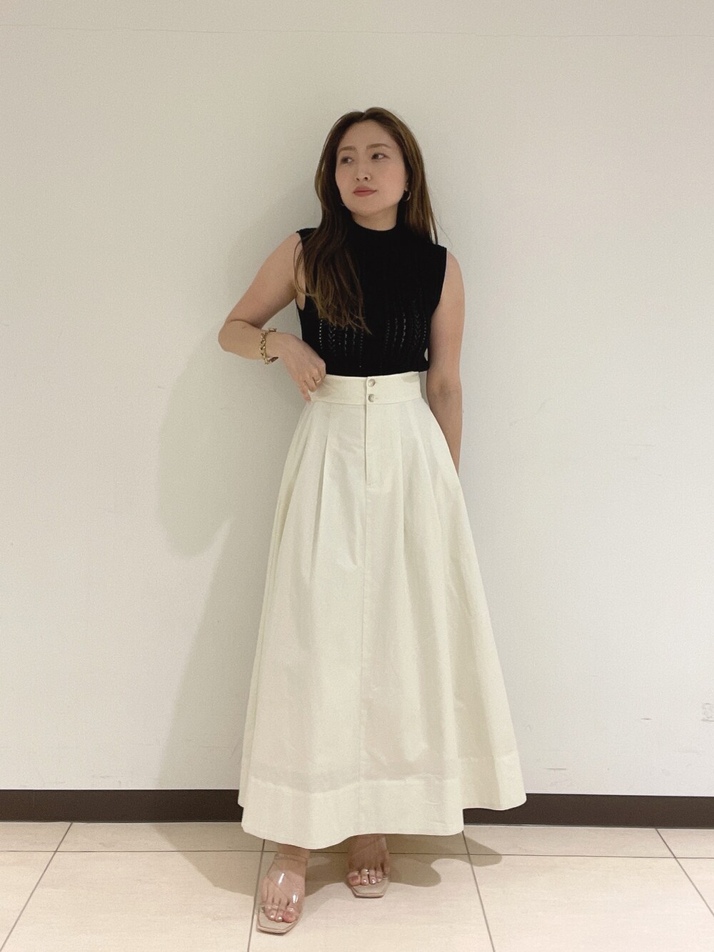 ブラック系のニット/セーター、ホワイト系のスカート、その他のサンダルを着用したレディースの夏コーディネートの2枚目の写真