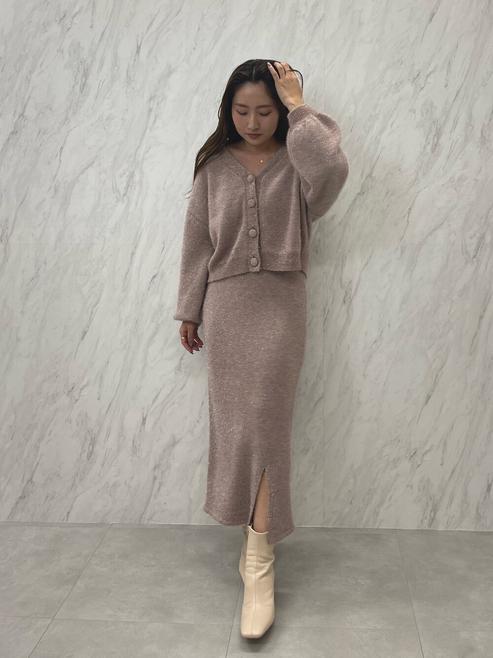 ピンク系のカーディガン/ボレロ、ピンク系のスカート、ホワイト系のブーツを着用したレディースの冬コーディネートの2枚目の写真