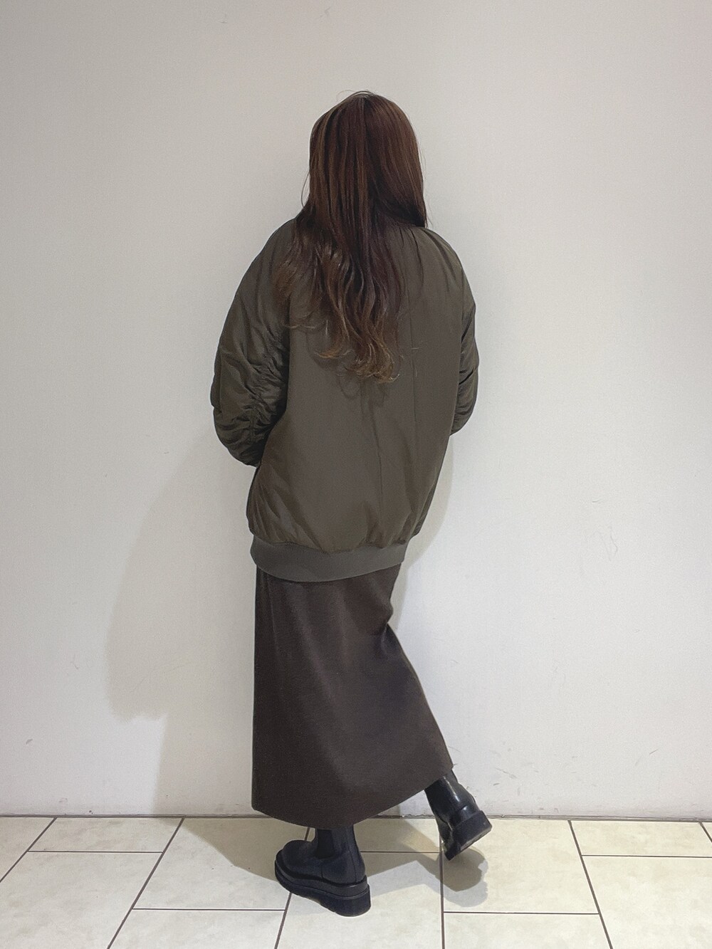 ブラウン系のニット/セーター、ブラウン系のスカート、ブラック系のブーツを着用したレディースの冬コーディネートの7枚目の写真