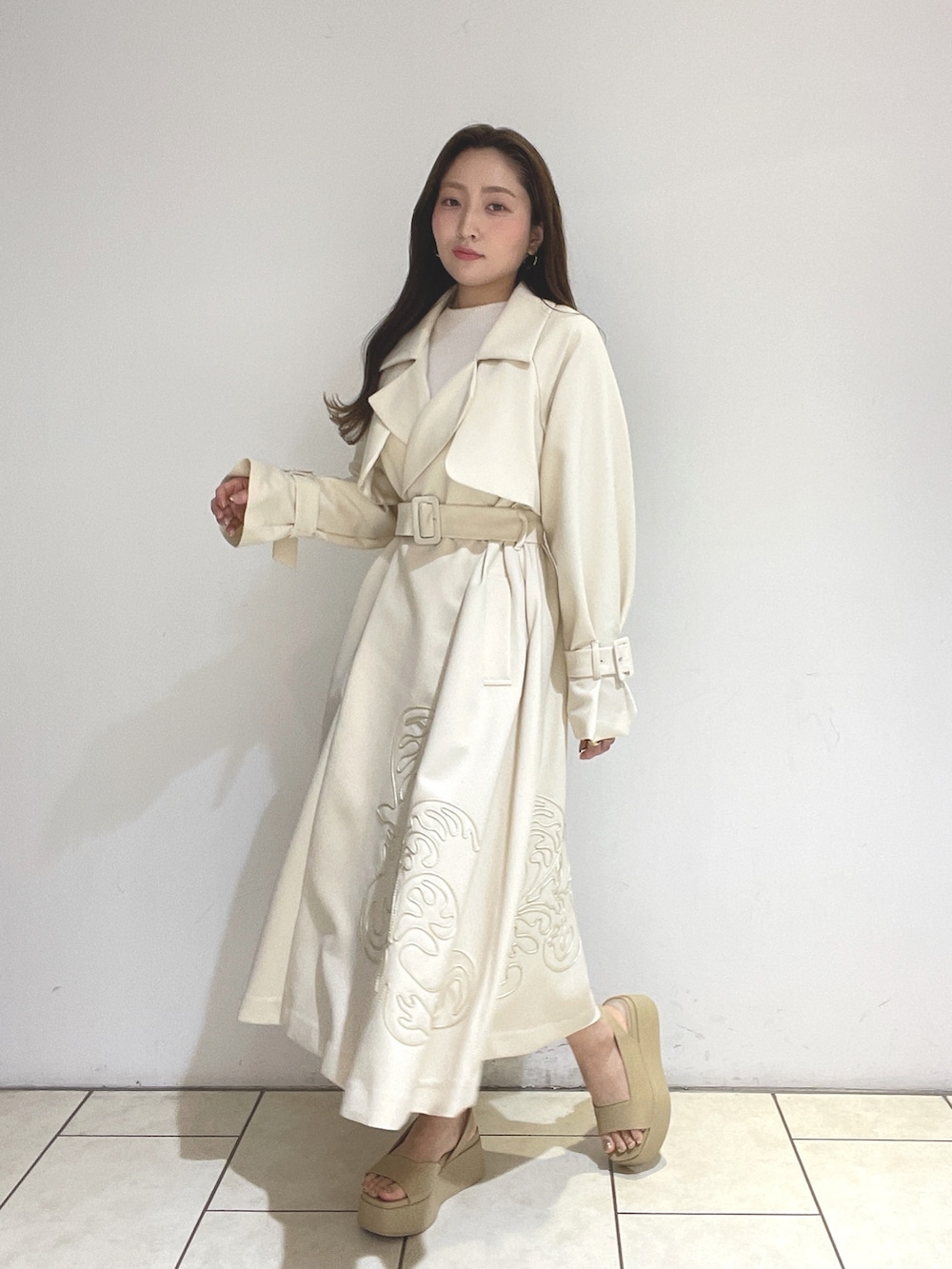 ホワイト系のトレンチコート、ベージュ系のサンダル、グリーン系のショルダーバッグを着用したレディースの冬コーディネートの4枚目の写真