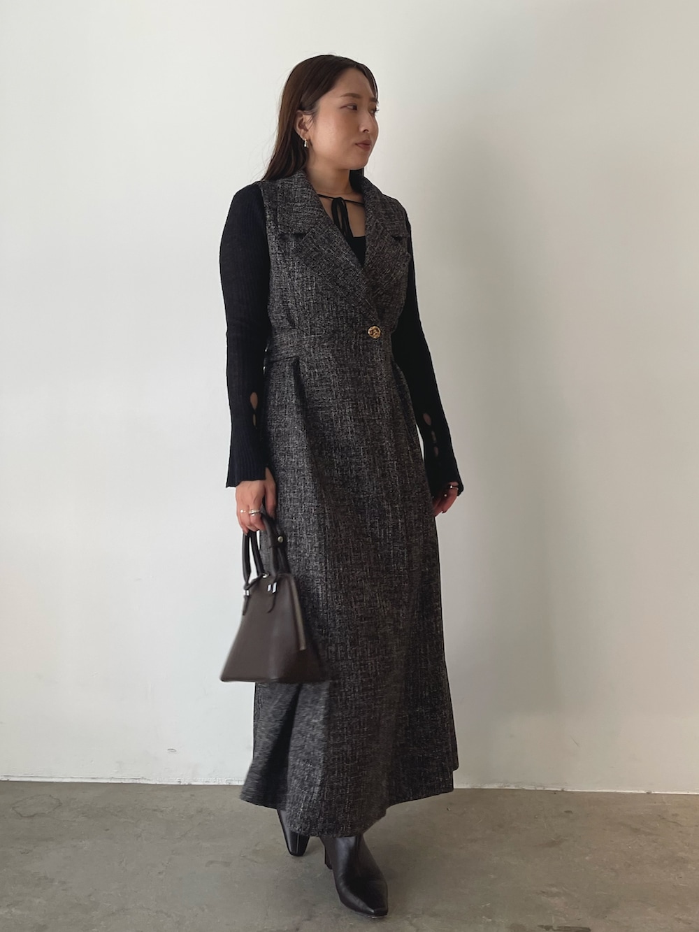 ブラウン系のブーツ、ブラウン系のボストンバッグ、ブラック系のニット/セーターを着用したレディースの秋コーディネートの2枚目の写真