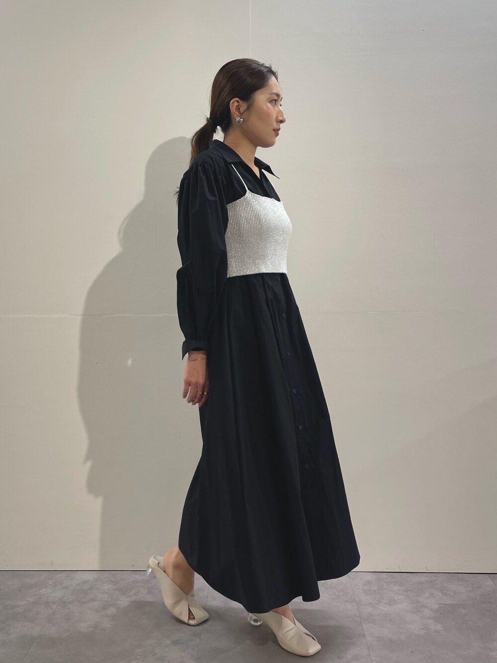 ホワイト系のパンプス、ブラック系のシャツワンピース、シルバー系のイヤリングを着用したレディースの冬コーディネートの2枚目の写真