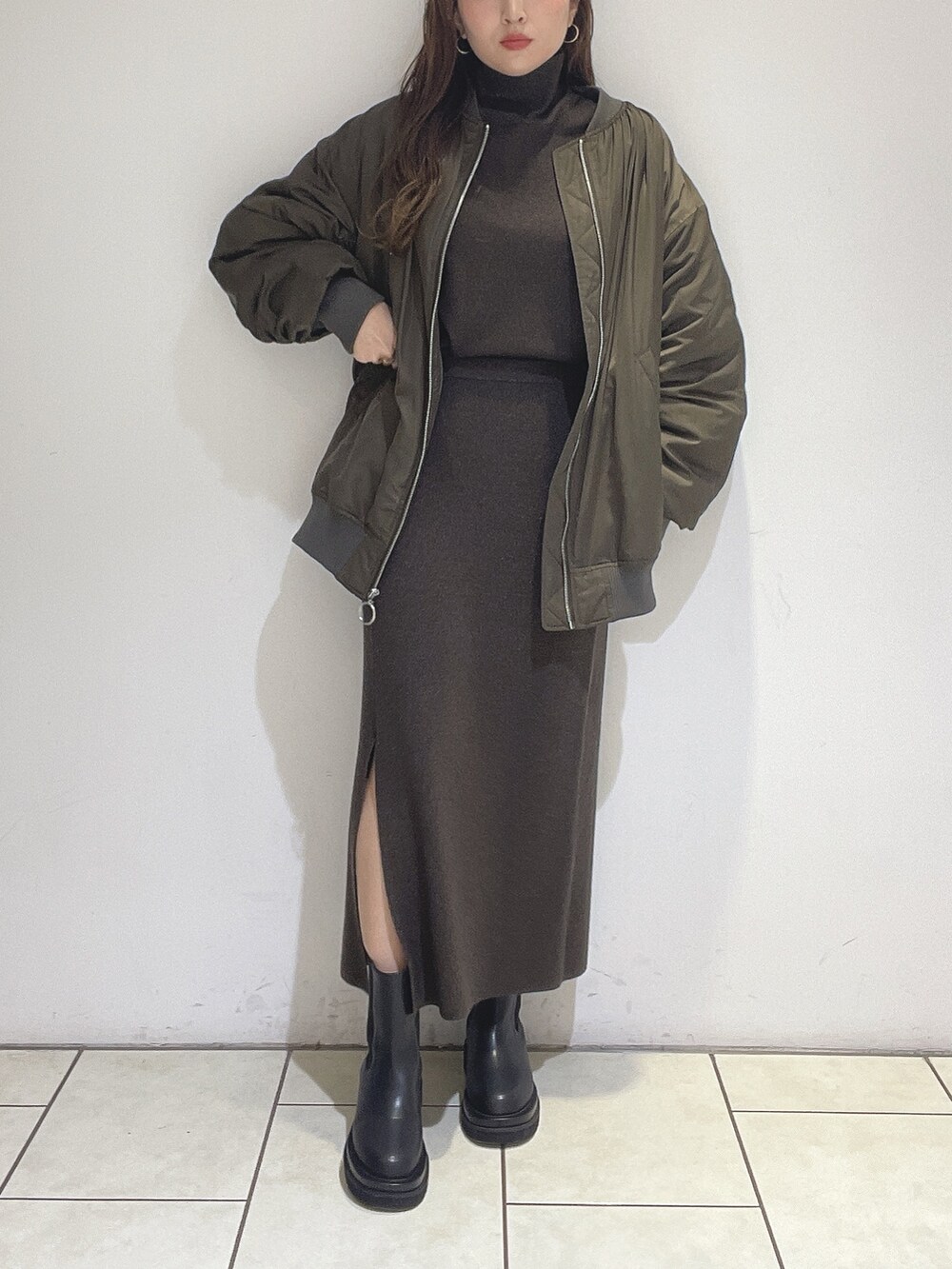 ブラウン系のニット/セーター、ブラウン系のスカート、ブラック系のブーツを着用したレディースの冬コーディネートの3枚目の写真