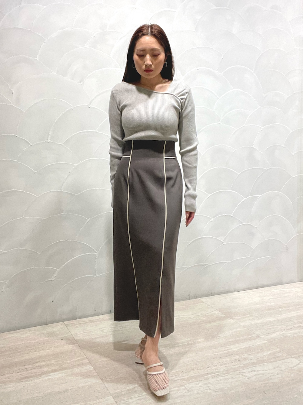 グレー系のスカート、ホワイト系のサンダル、グレー系のニット/セーターを着用したレディースの春コーディネートの7枚目の写真