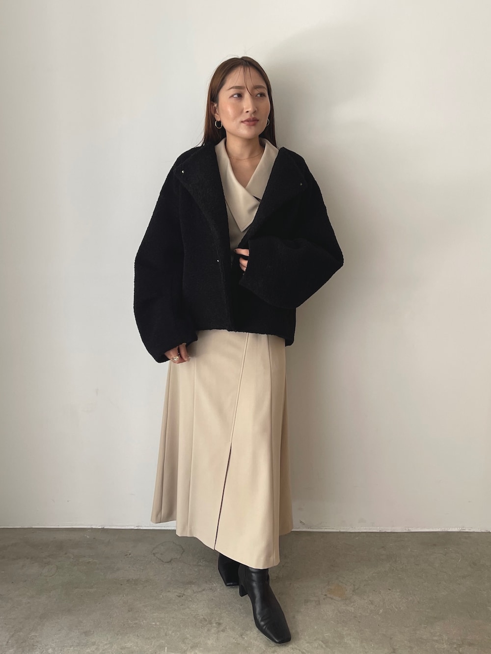 イエロー系のハンドバッグ、ブラック系のブルゾン、ベージュ系のワンピースを着用したレディースの秋コーディネートの2枚目の写真