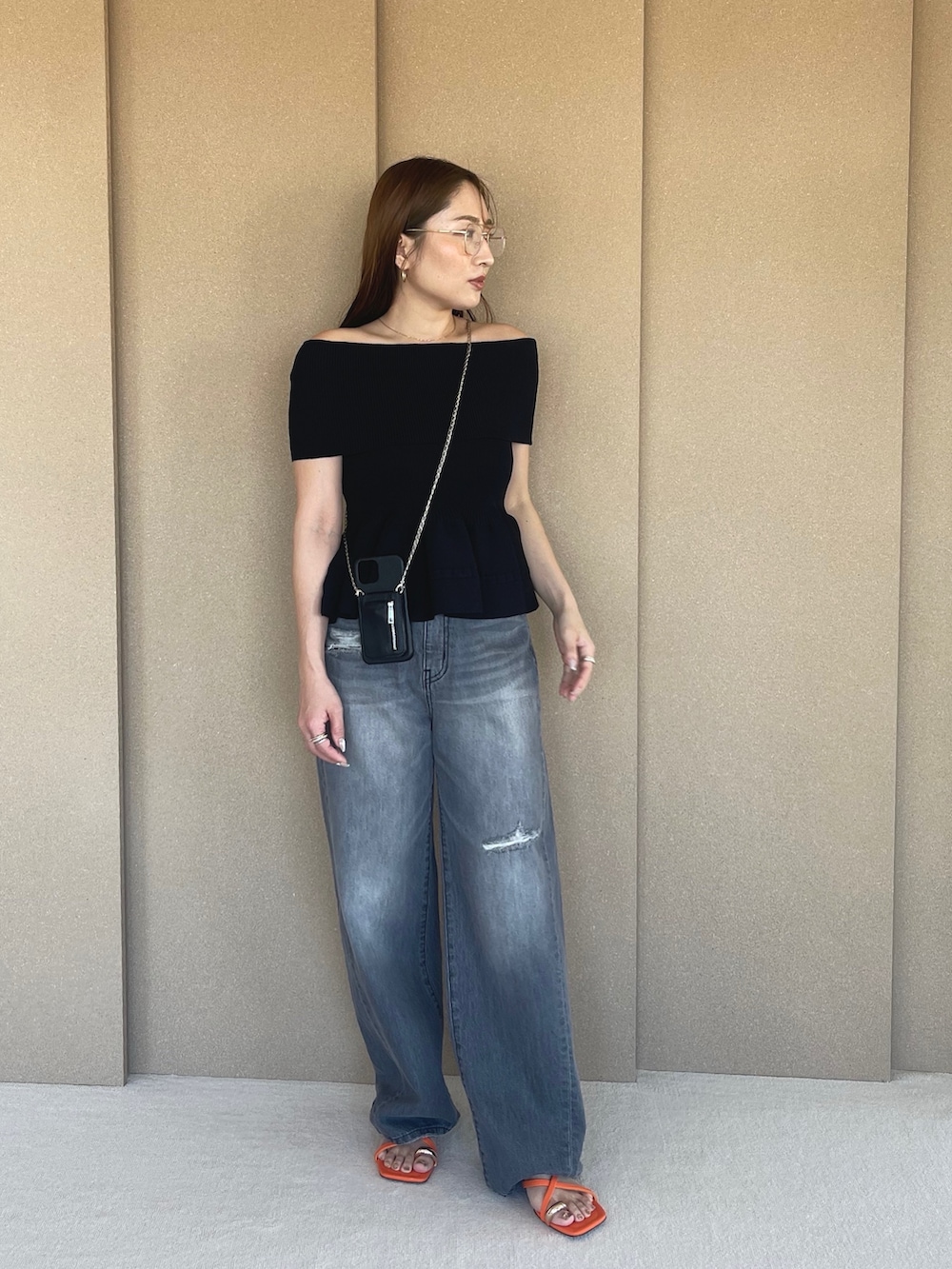 ブラック系のニット/セーター、グレー系のデニムパンツ、オレンジ系のサンダルを着用したレディースの春コーディネートの6枚目の写真