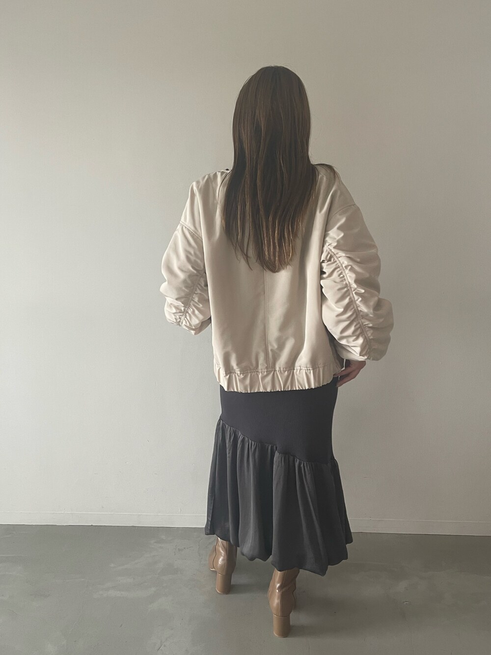 グレー系のワンピース、ベージュ系のブーツ、ホワイト系のブルゾンを着用したレディースの夏コーディネートの5枚目の写真
