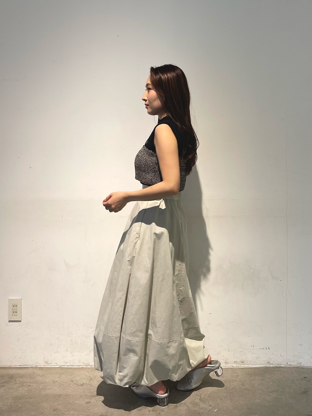 シルバー系のパンプス、ブラック系のニット/セーター、ホワイト系のスカートを着用したレディースの春コーディネートの6枚目の写真