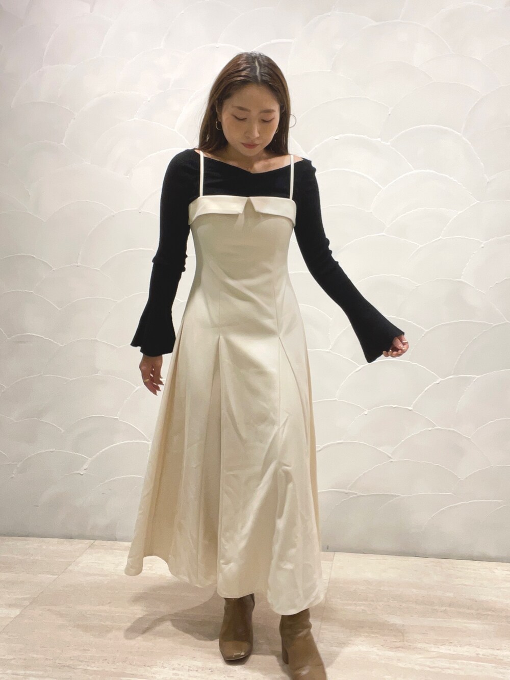 ベージュ系のブーツ、ブラック系のニット/セーター、ホワイト系のワンピースを着用したレディースの秋コーディネートの3枚目の写真